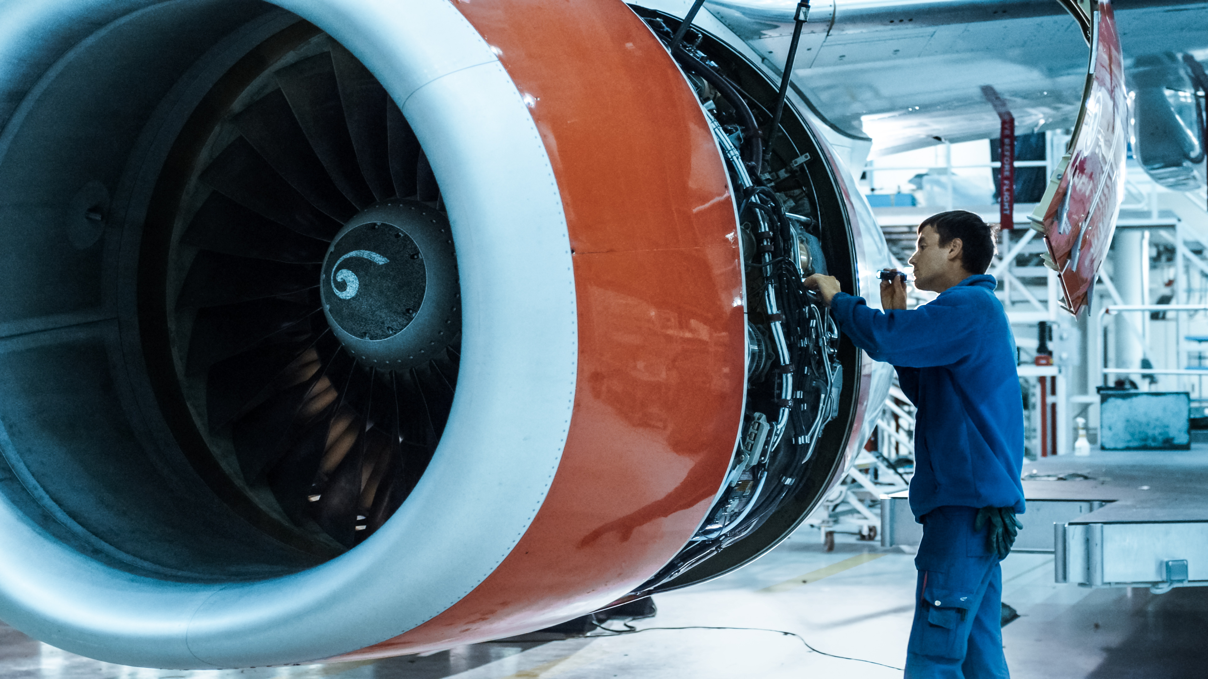 Aircraft maintenance mechanic inspects and tunes plane engine in a hangar. Aircraft maintenance mechanic inspects and tunes plane engine in a hangar.
